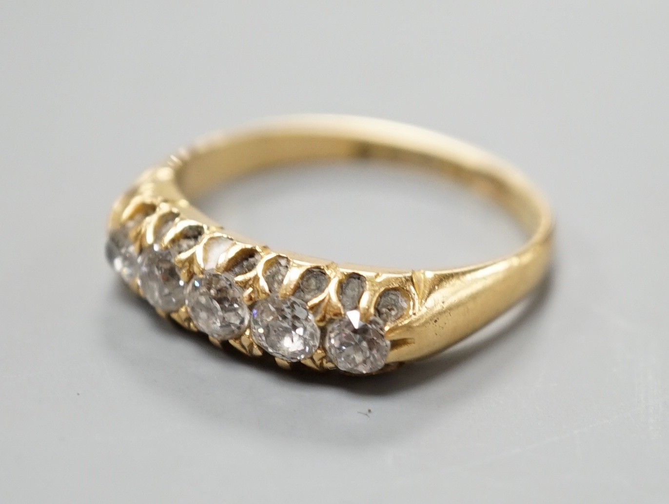 An early 20th century 18ct gold and graduated five stone diamond set half hoop ring, size N/O, gross weight 3.7 grams.